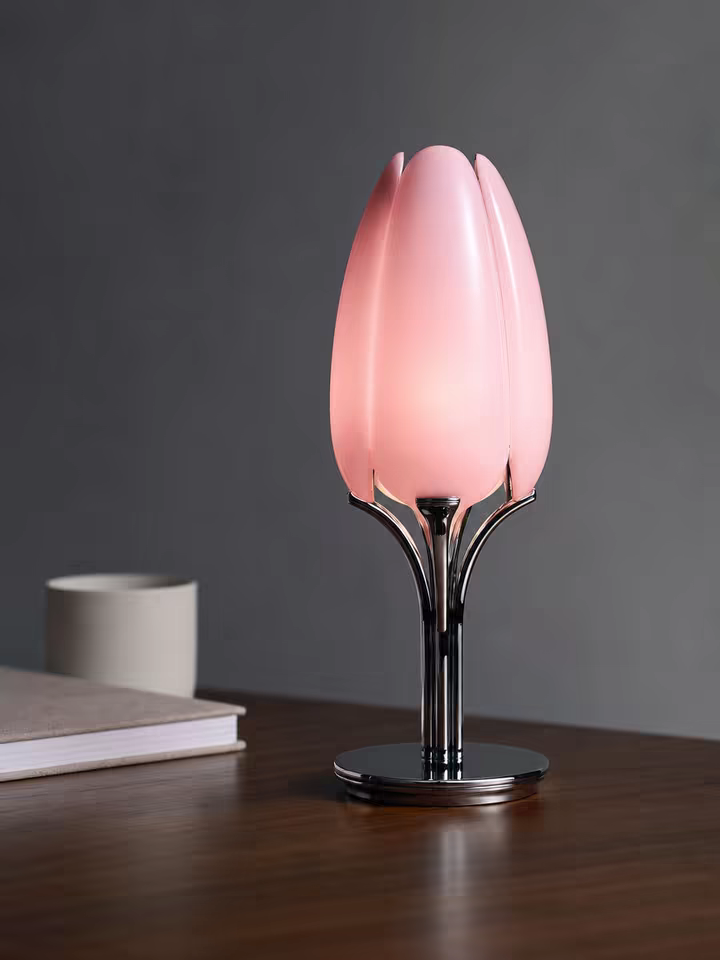 The lamp lit on a dark walnut desk beside a book and a ceramic cup