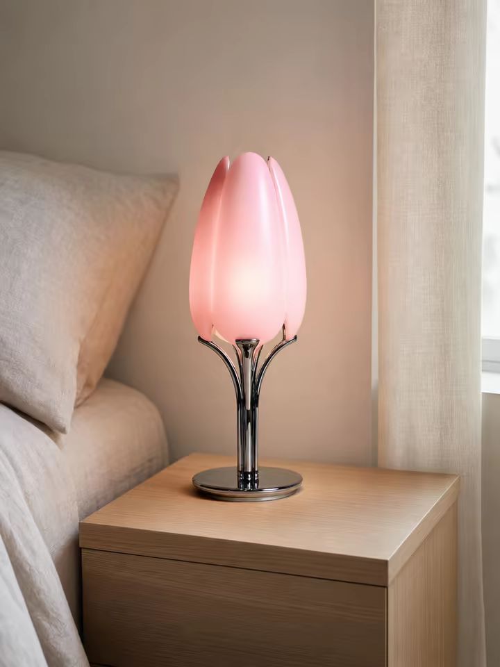 The lamp lit on a pale oak nightstand beside a made bed