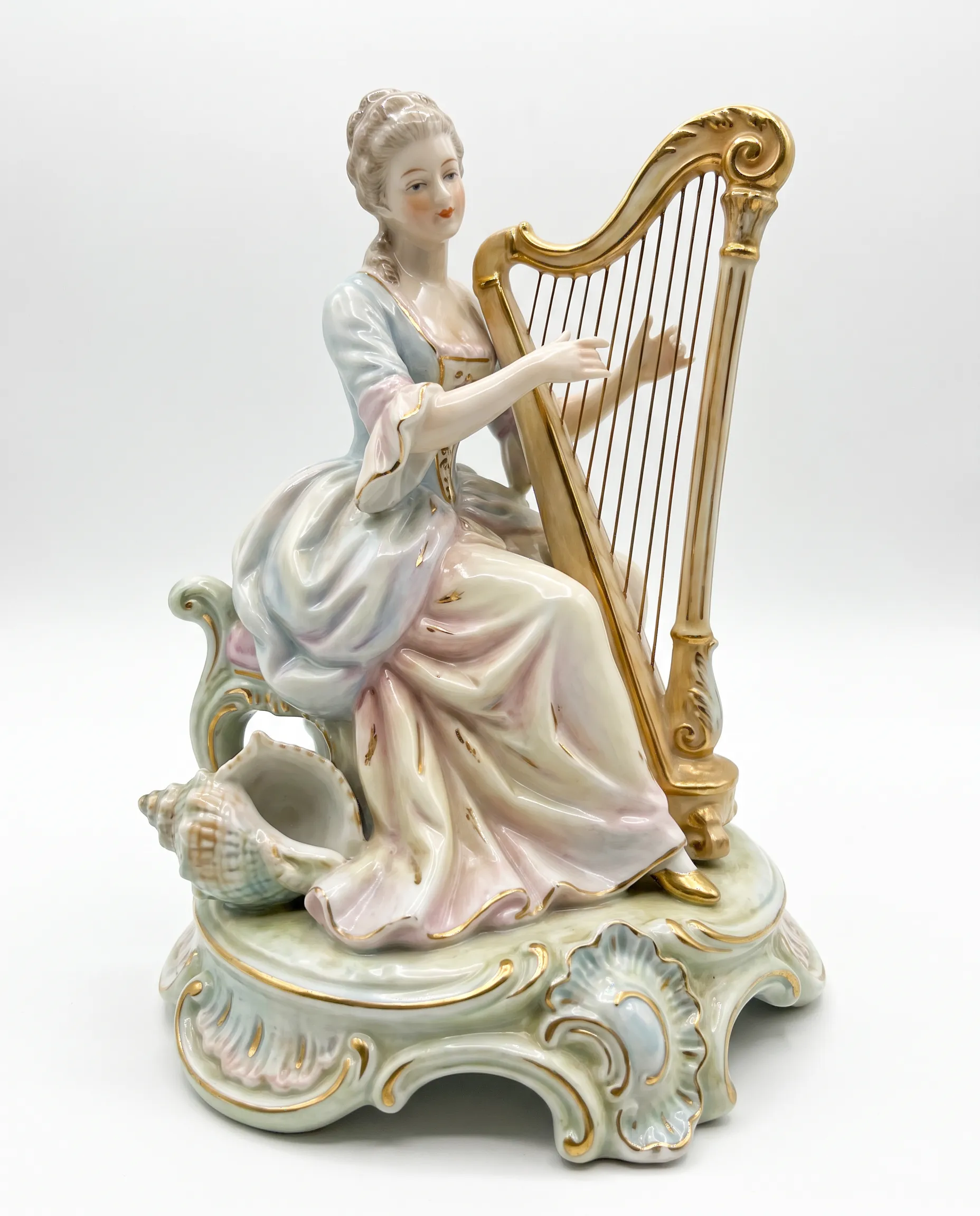 Porcelain figurine of a harpist on a shell and scroll base, rococo art style