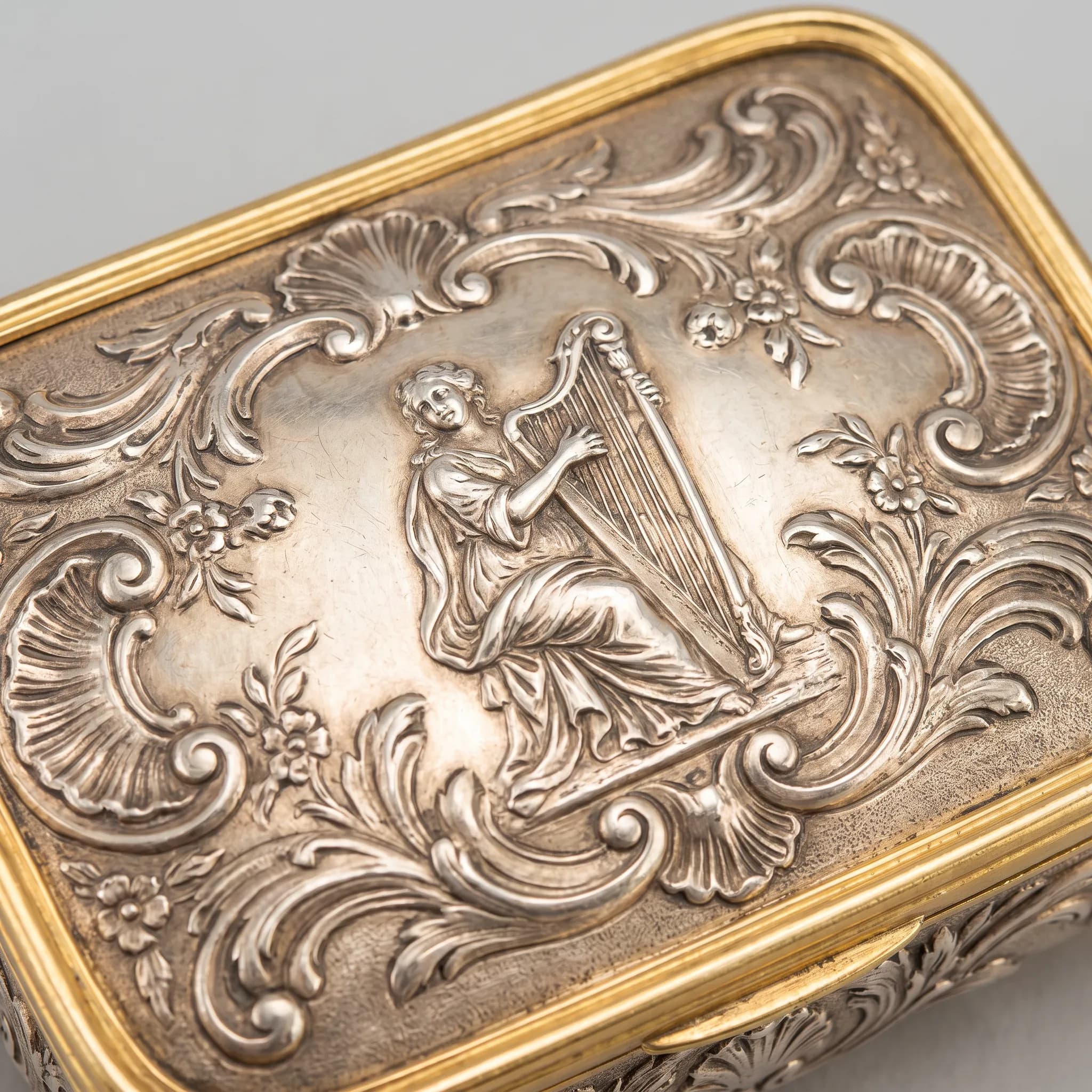 Chased silver box lid with a harpist in low relief among shells and scrolls, rococo art style