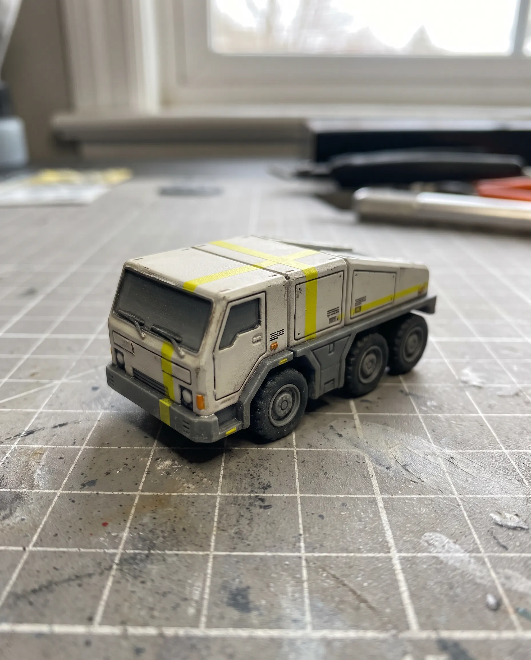 Painted resin scale model of a six-wheeled cargo tug on a cutting mat, macro photo in Marathon art style