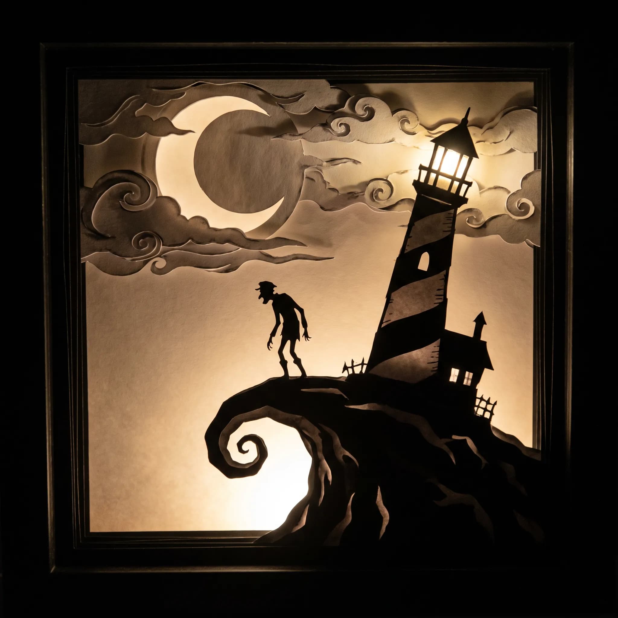 Layered black paper cutout shadow box of a thin lighthouse keeper on a curling cliff