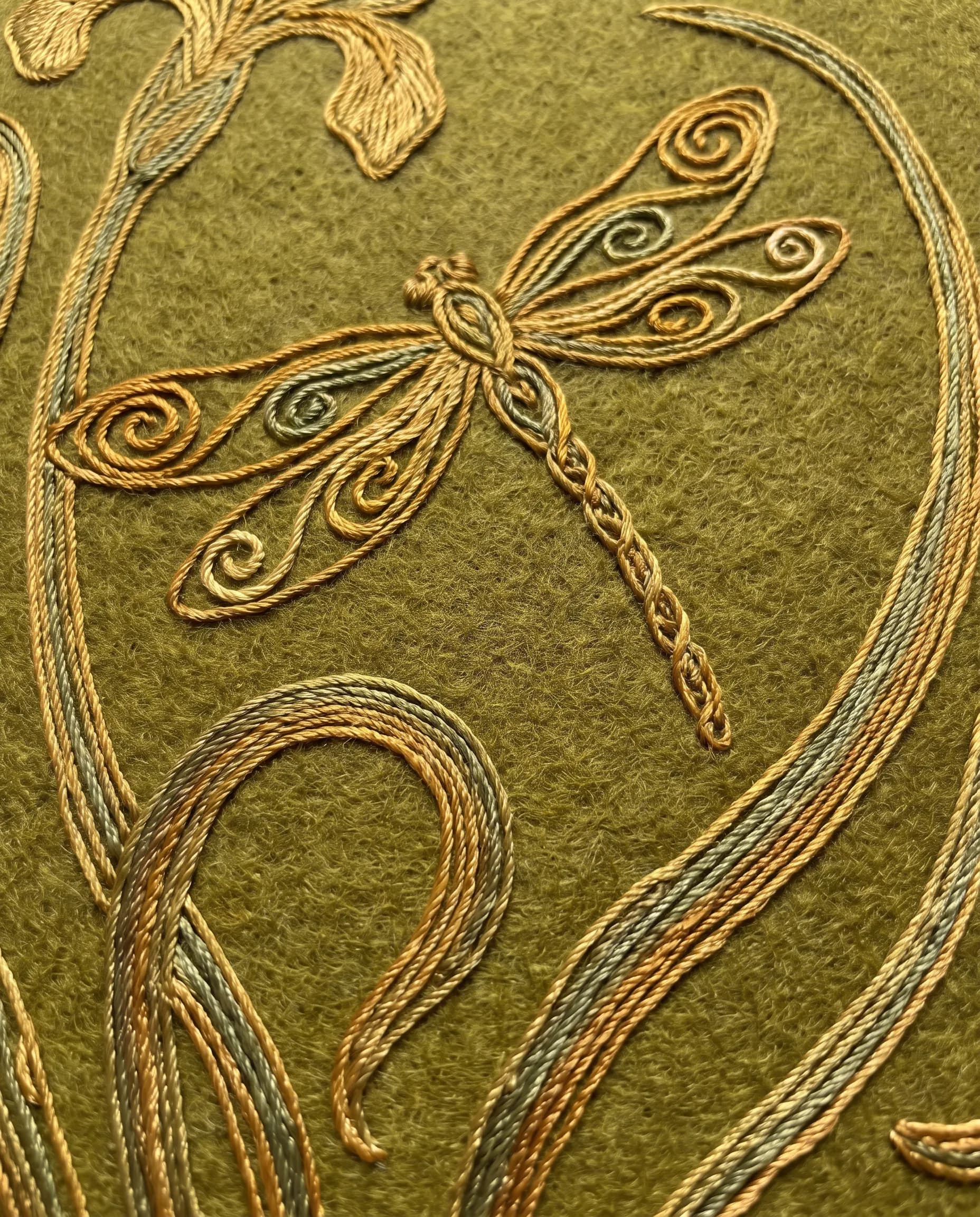 Silk embroidery on wool of a dragonfly above iris stalks