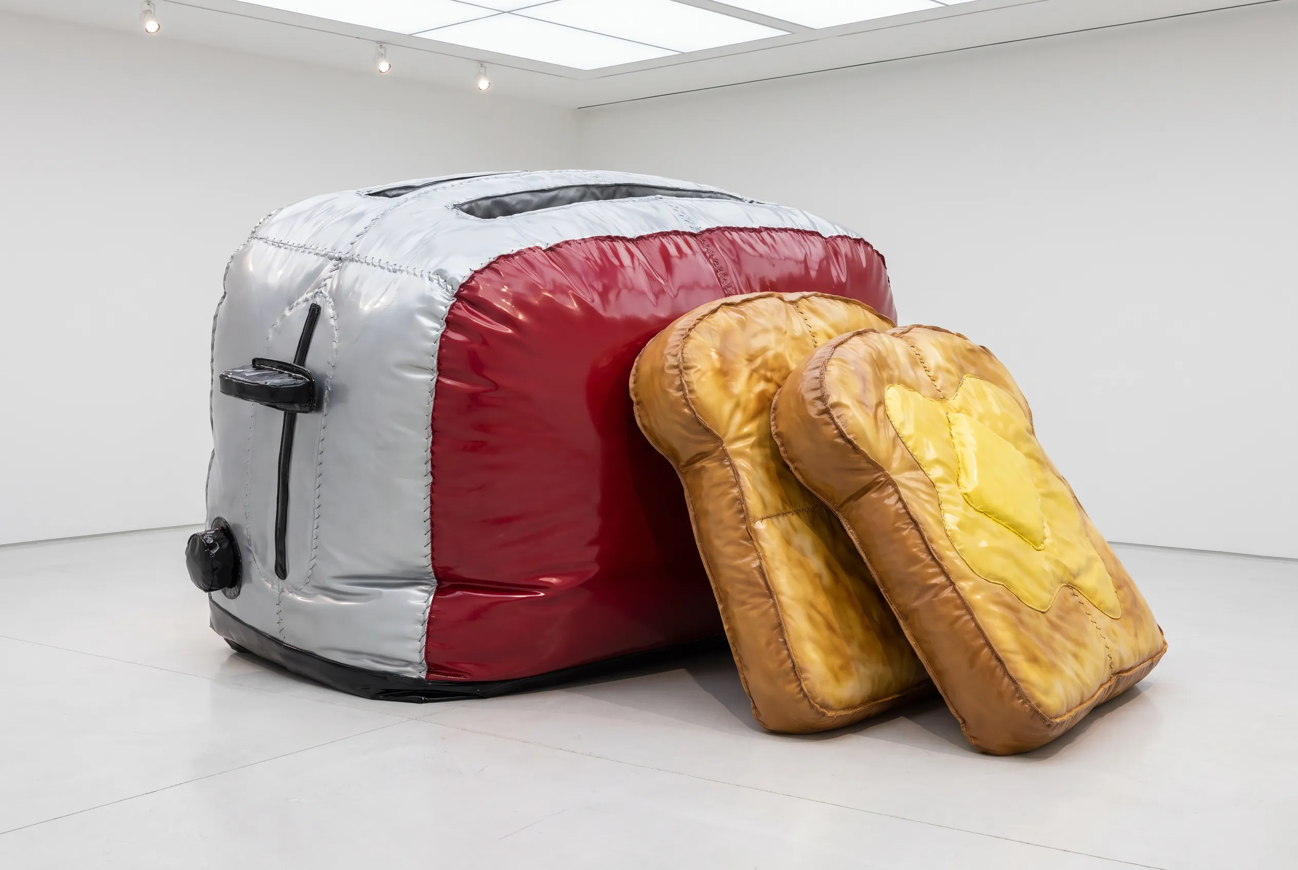Giant soft vinyl sculpture of a pop-up toaster slumped on a white gallery floor