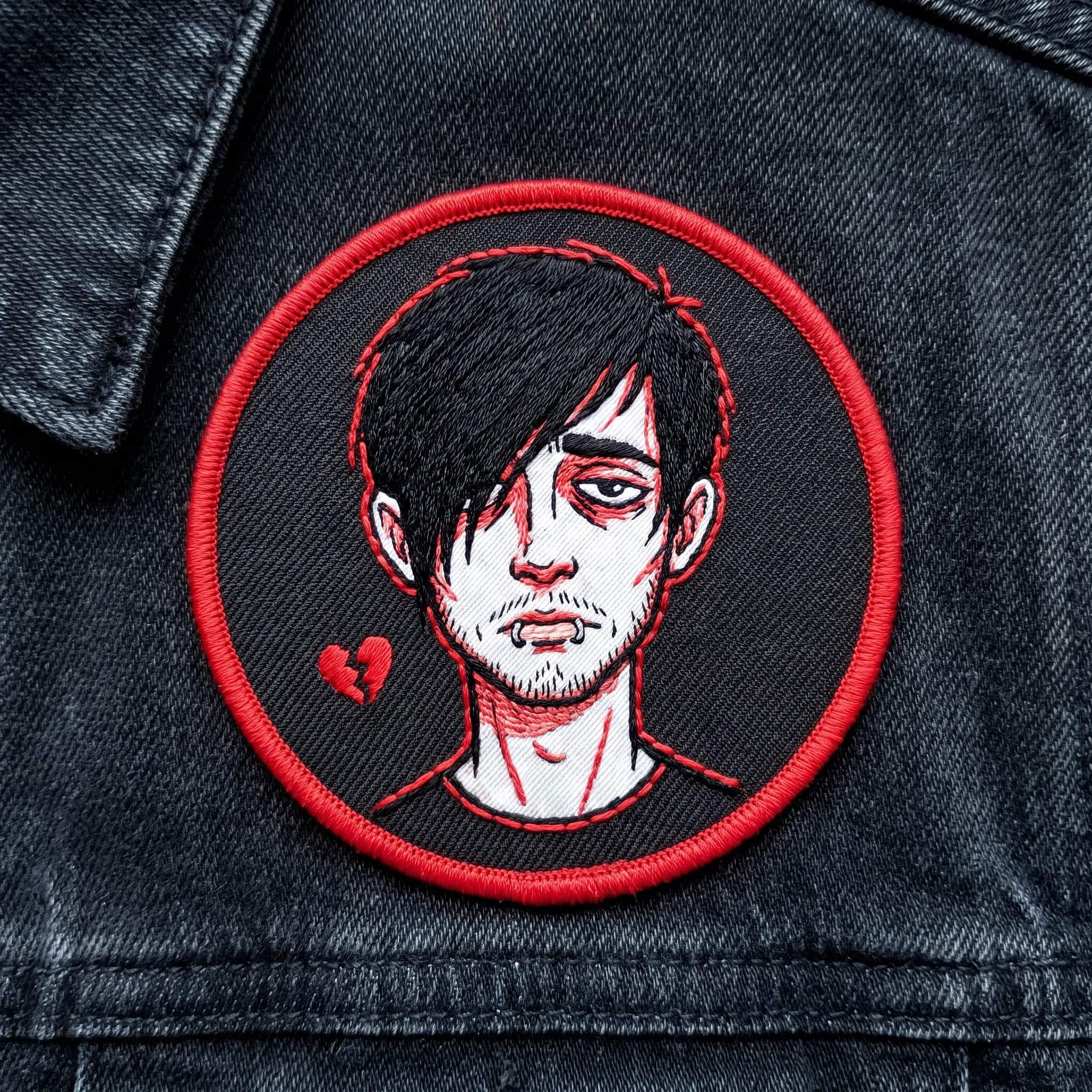 Embroidered patch in red and white thread of a stubbled man with a black fringe, emo art style