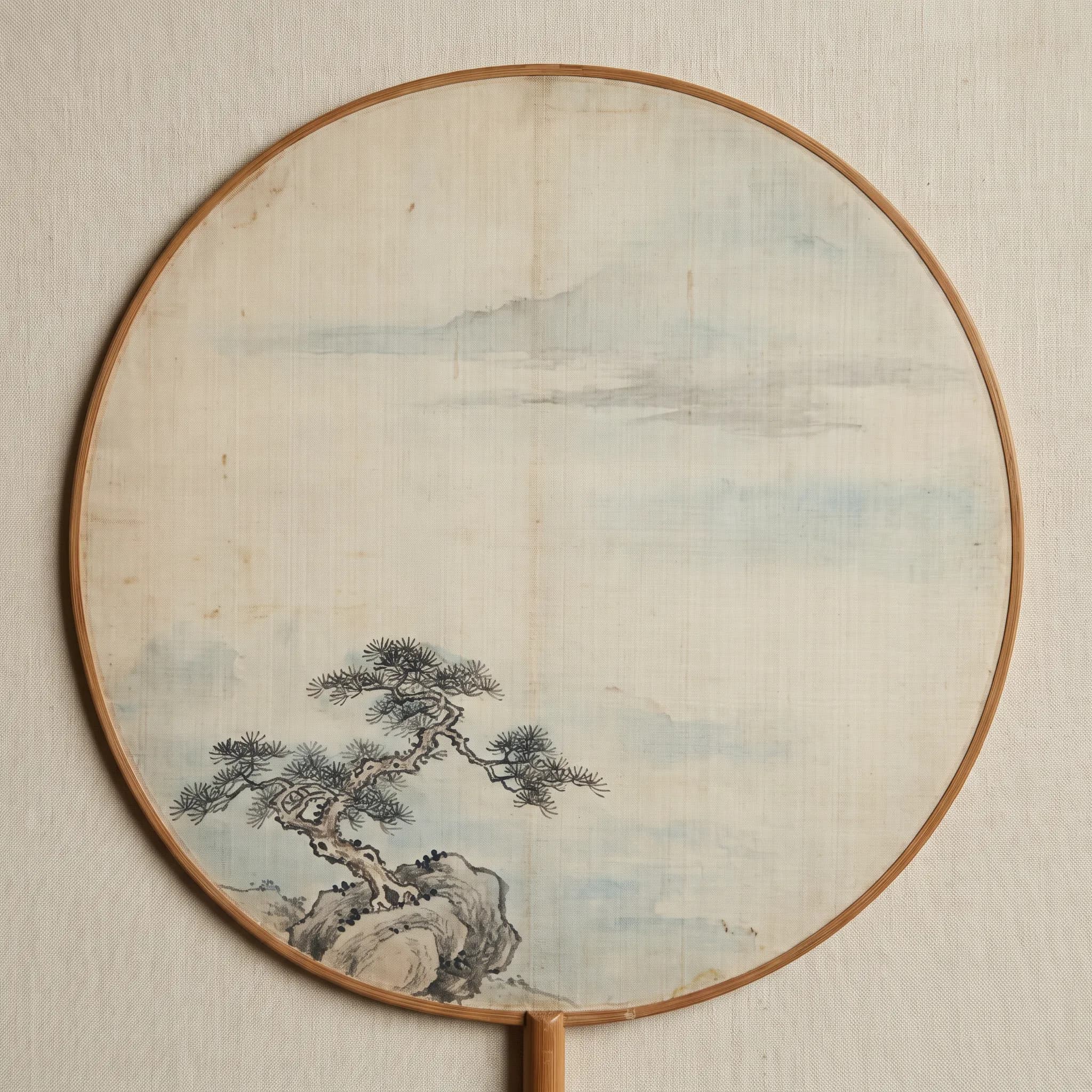 Round silk fan painted with a small pine on a boulder and misty empty space, traditional Chinese art style