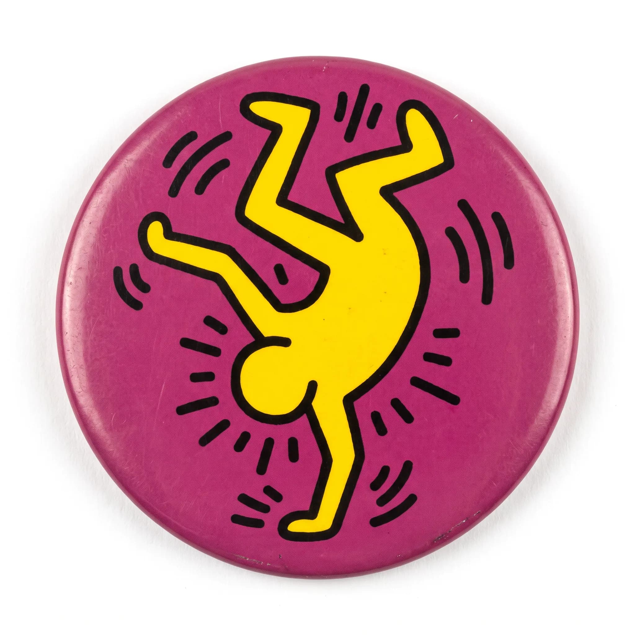 Round pin-back button with a yellow breakdancer on magenta, Keith Haring art style